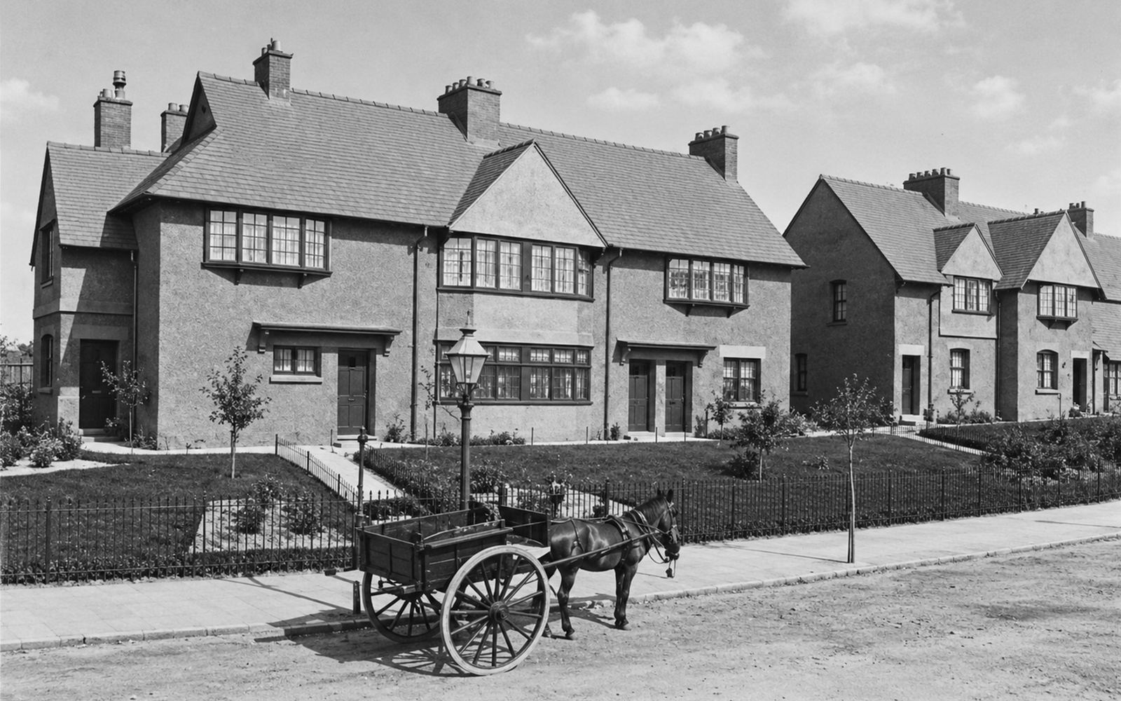 A pair of Victorian cottages with a horse and cart standing on the road outside